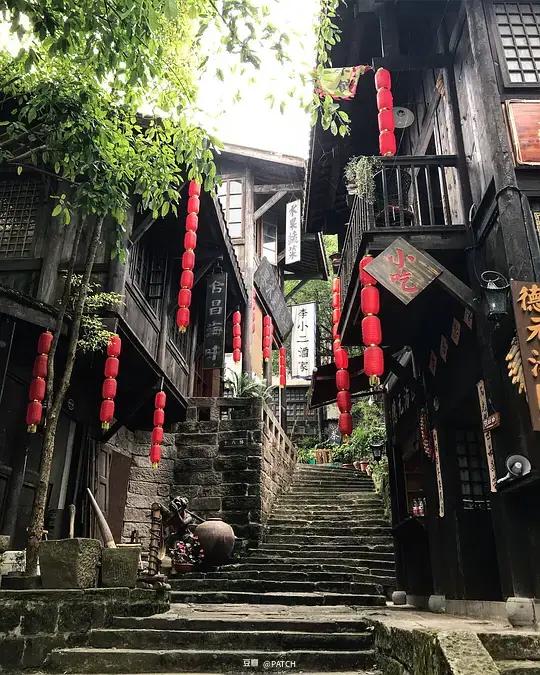 Stone steps between timber buildings and red lanterns in Shibati